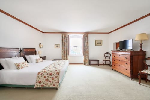 Spacious bedroom at Quinta da Alcaidaria-Mór near Fátima with wooden furniture, floral bedding and elegant décor