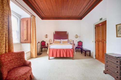 Elegant bedroom at Quinta da Alcaidaria-Mór with wooden ceiling, coral accents, and period furniture near Fátima