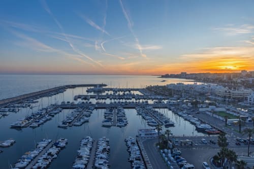 Puerto de Málaga al atardecer con veleros amarrados, marina y paisaje costero de la ciudad