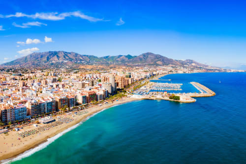 Vista aérea de la costa de Málaga con aguas turquesas, playa de arena y montañas al fondo