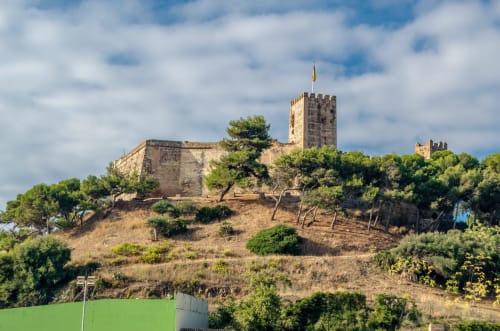Fortaleza medieval en la ladera con vistas a Málaga, torre de piedra y fortificaciones
