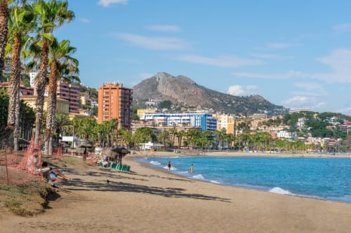 Vista frente al mar de los Apartamentos Ab Be en Málaga con palmeras, playa de arena y sierra al fondo