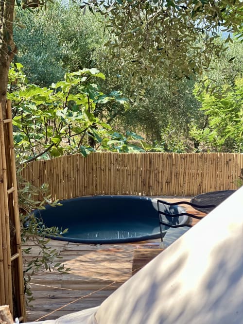 Vasque thermale bleue sur terrasse en bois, entourée d'oliviers et de clôture bambou au jardin de l'Agritourismo Stecadò à Dolceacqua
