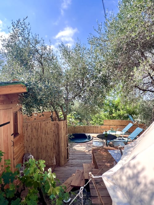 Patio du jardin d'oliviers à l'Agritourisme Stecadò à Dolceacqua avec terrasse en bois, transats et jacuzzi sous ciel bleu