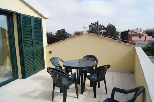 Rooftop terrace with black dining furniture overlooking Orosei, Italy - apartment veranda with city views
