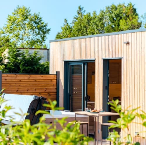 Modern glamping cabin at Ilot Cosy and Spa with corrugated metal exterior, wooden deck, and forest views in Luçay-le-Mâle