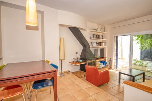 Salon moderne à Finques Garcia Enrich à Palafrugell avec table de salle à manger, fauteuil rouge, foyer et accès au jardin