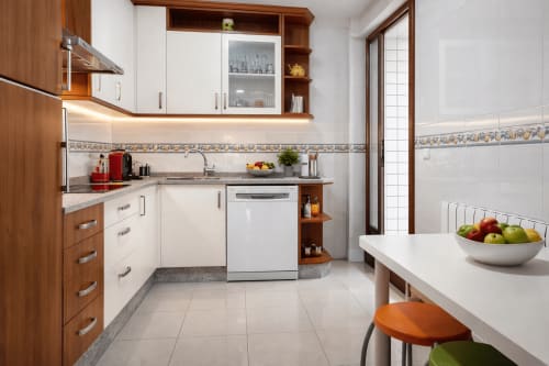 Cocina moderna en apartamento Chuliña, Baiona con muebles de madera, encimeras blancas, electrodomésticos acero inoxidable y comedor
