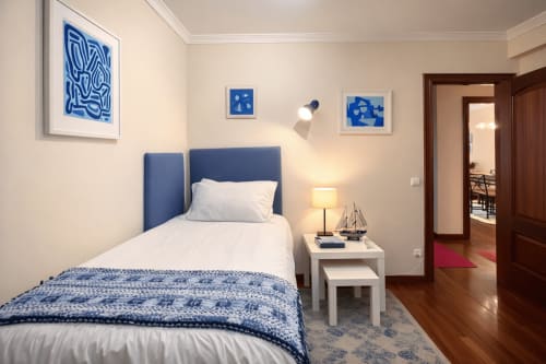 Dormitorio moderno con cabecero azul, ropa de cama blanca y arte temático náutico en Holibai Baiona