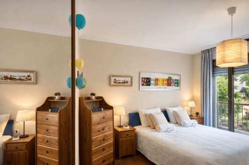 Dormitorio luminoso en apartamento Holibai con muebles de madera, ropa de cama blanca y vistas al balcón en Baiona