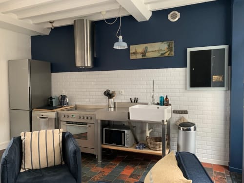 Cuisine cottage moderne avec carrelage métro blanc, murs bleu foncé, électroménagers inox et coin salon aux Filles