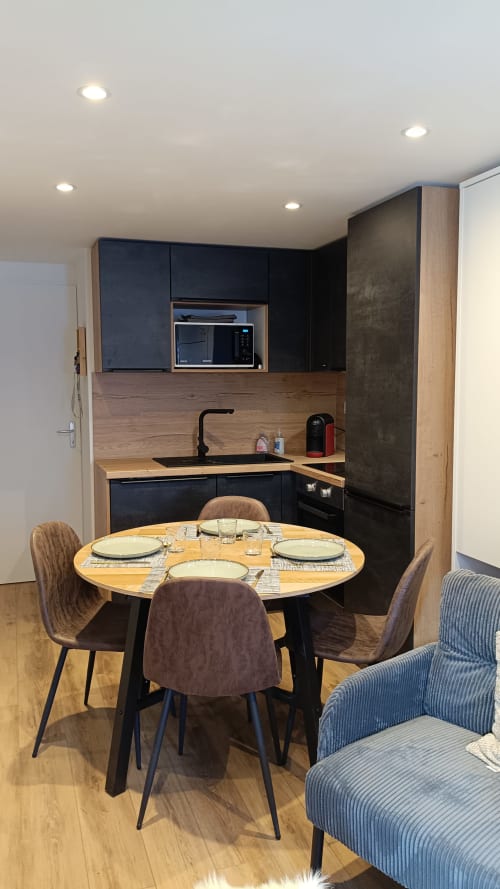 Cuisine-salle à manger moderne du gîte avec table ronde, mobilier noir et accents en bois