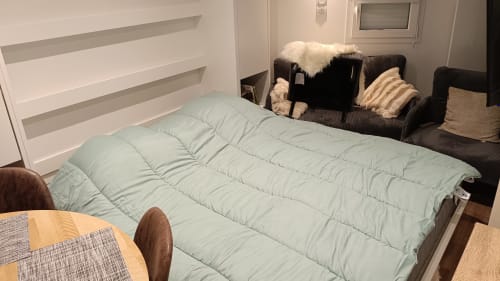 Chambre moderne au Gîte des Gônes à Feyzin avec lit matelassé bleu clair et canapé noir aux coussins