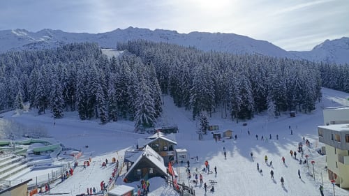 Station de ski enneigée avec forêt alpine, montagnes et pistes de ski en destination hivernale