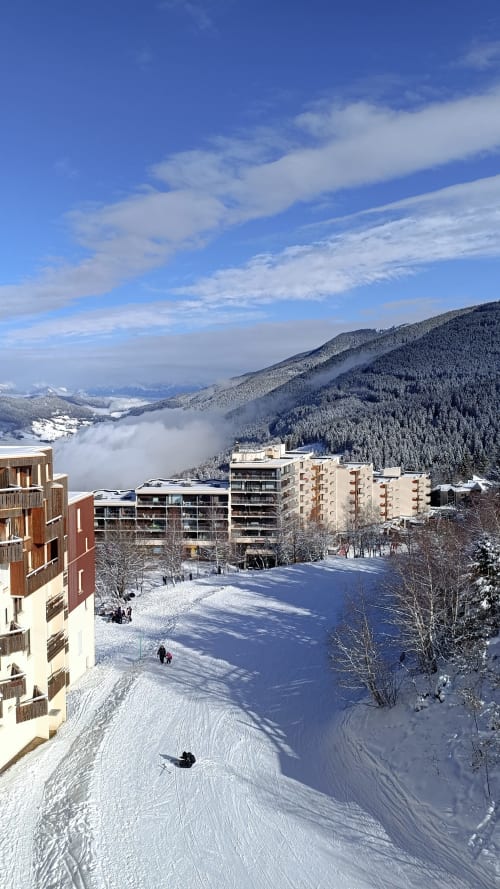 Piste de ski enneigée avec immeubles d'appartements et montagnes boisées au Gîte des Gônes, Feyzin