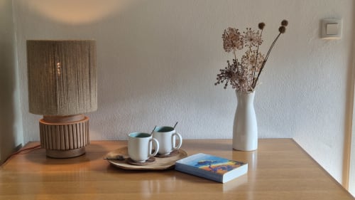 Minimalistisch interieur bij Moulin Renaudiots Autun: houten bureau met witte vaas, droogbloemen, lamp en boeken