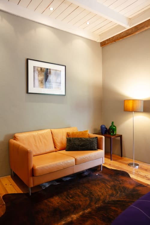 Moderne lounge met oranje lederen bank en vloerlamp in de Rolin-kamer van Hotel Moulin Renaudiots, Autun