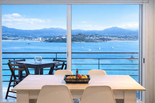 Amplia terraza para cenar con vistas al mar de Baiona, España, con mesa de madera y cómodos asientos