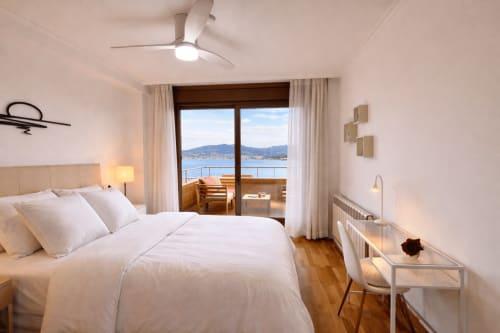 Habitación moderna en Holibai Baiona con vistas al mar, ropa de cama blanca y terraza con vistas al agua y montañas
