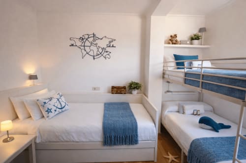 Dormitorio con temática náutica en Holibai, Baiona, con camas gemelas, acentos azules, mapamundi en la pared y vistas al mar.