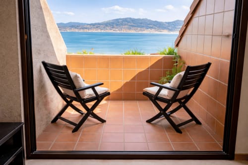 Dos sillas negras en terraza de terracota con vistas al mar mar,  de Baiona, apartamento Arco Da Vella