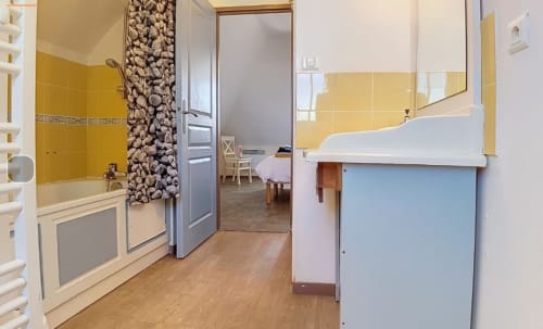 Salle de bains aux carreaux jaune vif avec baignoire, lavabo et miroir à Locations Loc'Maria à Belle-Île-en-Mer