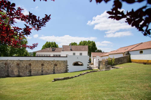 Quinta da Alcaidaria-Mór guesthouse courtyard with manicured lawn, stone walls and terracotta roofing in Ourém, Portugal