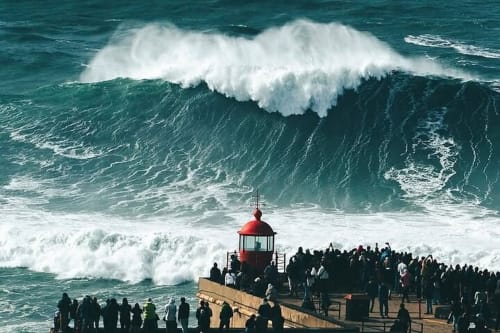 Giant ocean wave with red lighthouse and crowds at Ourém-Fátima coastal viewpoint