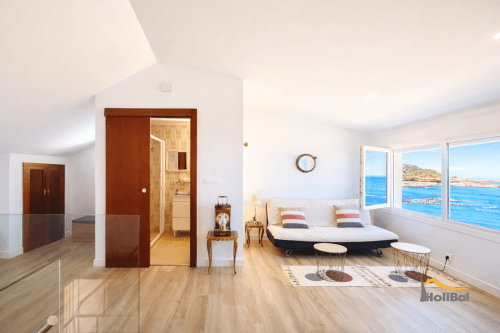 Habitación Duplex Albatros en Baiona con vistas al mar, suelos de madera, cama moderna y ventanales panorámicos con vista a la bahía
