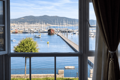 Vista marina de Baiona desde el balcón del apartamento Solpor con veleros y montañas, hotel Holibai