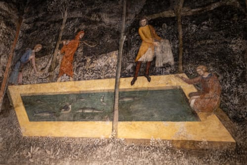 Ancient fresco at Le Prieuré Notre-Dame showing figures around a pool with fish, Montfrin France