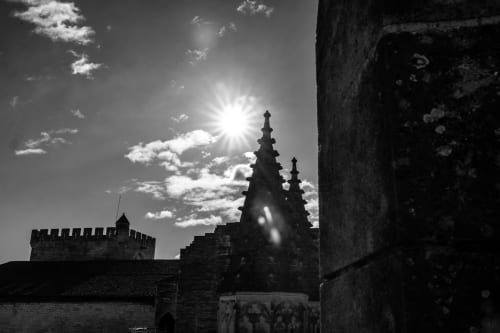 Medieval stone architecture and church spires at Le Prieuré Notre-Dame in Montfrin, France, backlit by bright sunshine