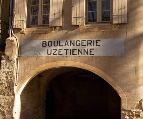 Boulangerie Uzetienne storefront entrance in Montfrin, France with arched doorway and shuttered windows