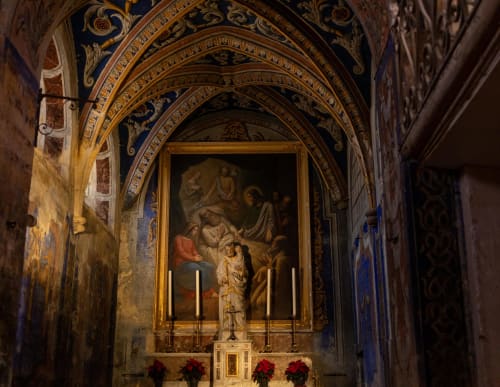 Ornate chapel interior at Le Prieuré Notre-Dame with arched ceiling, religious artwork, and red poinsettias in Montfrin