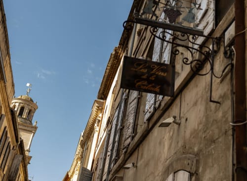 Historic street facade of Le Prieuré Notre-Dame in Montfrin, France, with ornate balconies and tower