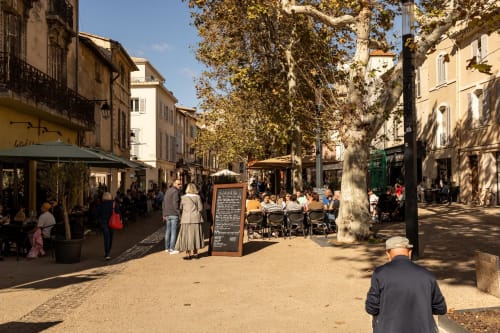 Charming town square in Montfrin, France with tree-lined plaza, café seating, and historic buildings near Le Prieuré