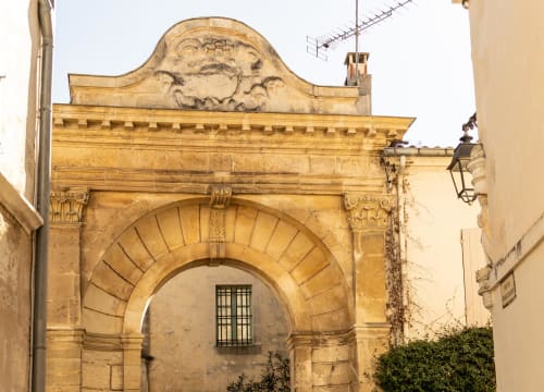 Historic stone archway with ornate carved pediment at Le Prieuré Notre-Dame, Montfrin, France