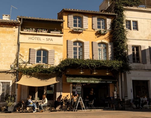Le Prieuré Notre-Dame hotel-spa in Montfrin with yellow facade, garden café, and outdoor seating