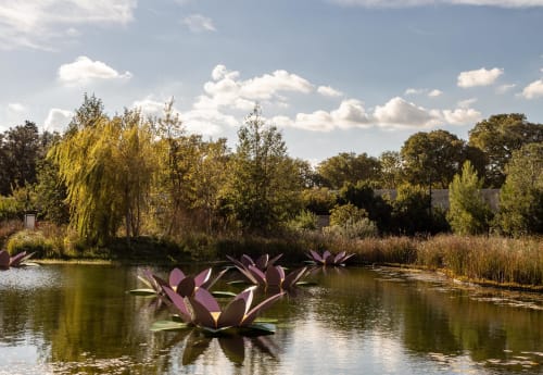 Purple lotus sculptures in pond at Le Prieuré Notre-Dame, Montfrin France with trees and sky