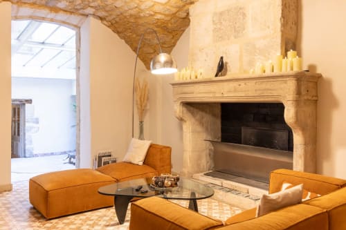 Luxury lounge at Le Prieuré Notre-Dame B&B in Montfrin with stone fireplace, tan leather seating, and arched ceiling