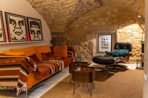 Modern rustic living room at Le Prieuré Notre-Dame in Montfrin with stone walls, orange seating, and contemporary art