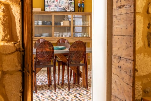 Dining room at Le Prieuré Notre-Dame with round table, wooden chairs, glass cabinet, and patterned floor in Montfrin