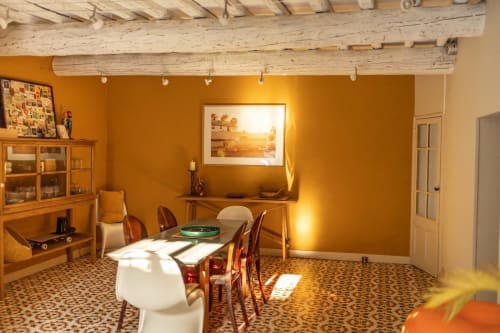 Warm mustard-yellow dining room at Le Prieuré Notre-Dame with wooden beams, framed artwork, and period furniture