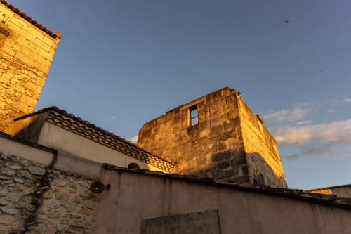 Historic stone tower at Le Prieuré Notre-Dame in Montfrin, France, lit by golden sunset light