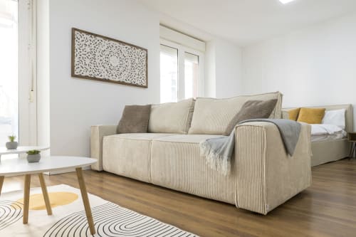 Moderno salón de apartamento en Málaga con sofá beige, mesa de madera y vistas a la ciudad desde el balcón