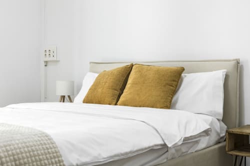 Dormitorio moderno con cabecera beige, ropa de cama blanca y almohadas doradas en Ab Be Apartments, Málaga