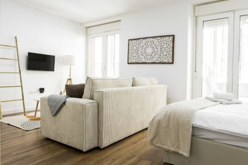 Moderno apartamento estudio en Málaga con sofá de rayas crema, cama, TV y puertas al balcón con vistas a la ciudad