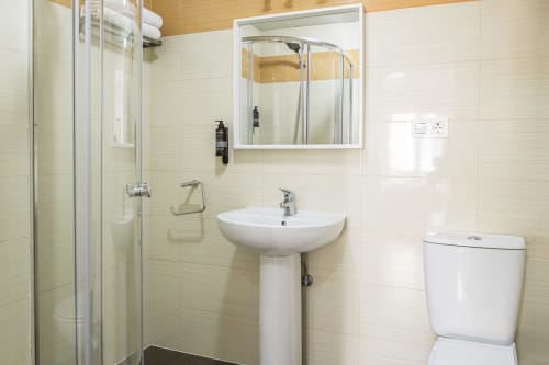 Baño moderno en apartamento Ab Be Special Home, Málaga, con lavabo pedestal, ducha, inodoro y espejo.