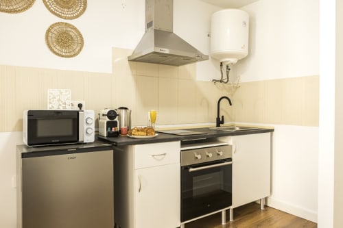 Cocina moderna en Ab Be Apartments Málaga con muebles blancos, electrodomésticos de acero inoxidable y microondas