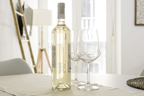 Botella de vino blanco con dos copas vacías sobre la mesa de comedor en Ab Be Apartments, Málaga
